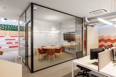 Sala de reunião com uma mesa central de madeira clara e cadeiras de design contemporâneo. Painéis de madeira escura nas paredes e uma iluminação suave evocam o equilíbrio zen japonês em um espaço corporativo moderno.