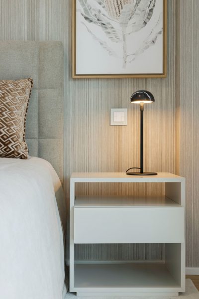 Mesa de cabeceira branca que oferece apoio durante a noite e o dia.