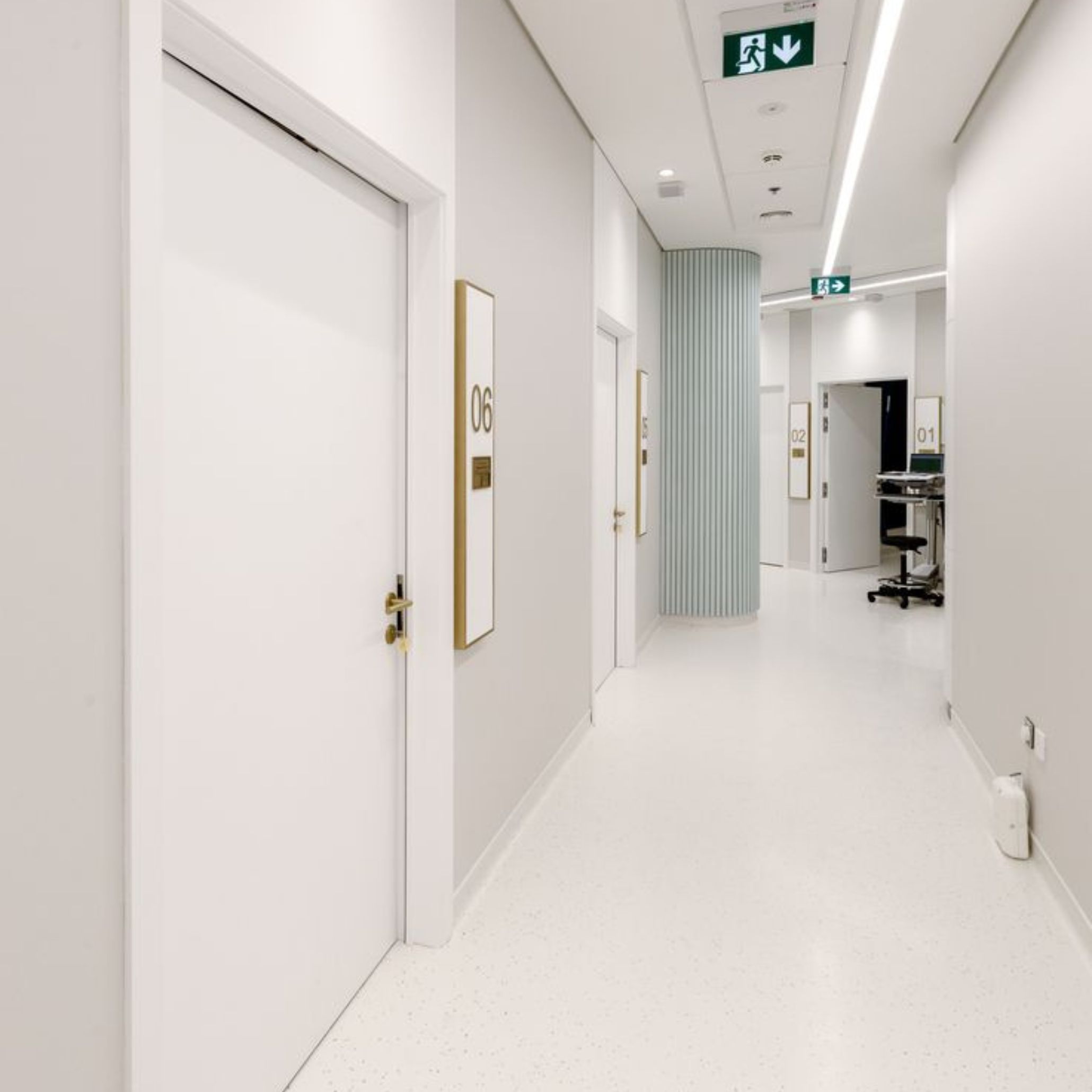 Corredor de estética clínica onde a psicologia das cores se manifesta em cores frias e impessoais, revelando como a psicologia das cores influencia a perceção de ambientes mais rígidos e menos acolhedores.