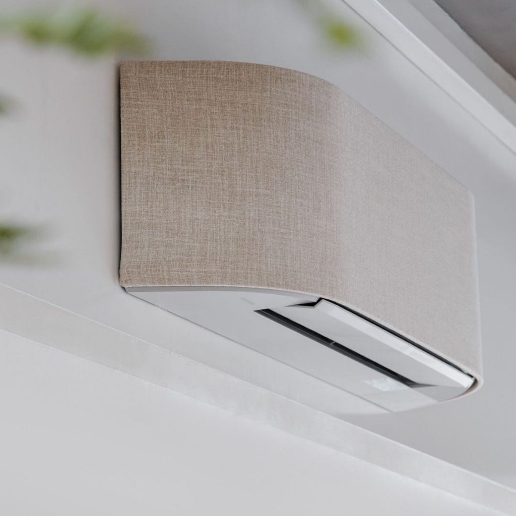 Unidade de ar condicionado integrada num design de interiores elegante, com cobertura têxtil que melhora o bem estar e reforça a saúde e bem estar ao harmonizar funcionalidade e estética. A solução discreta contribui para a saúde mental e promove bem estar, demonstrando como o design de interiores pode elevar a saúde e bem estar e criar um ambiente visualmente sereno que apoia a saúde mental.