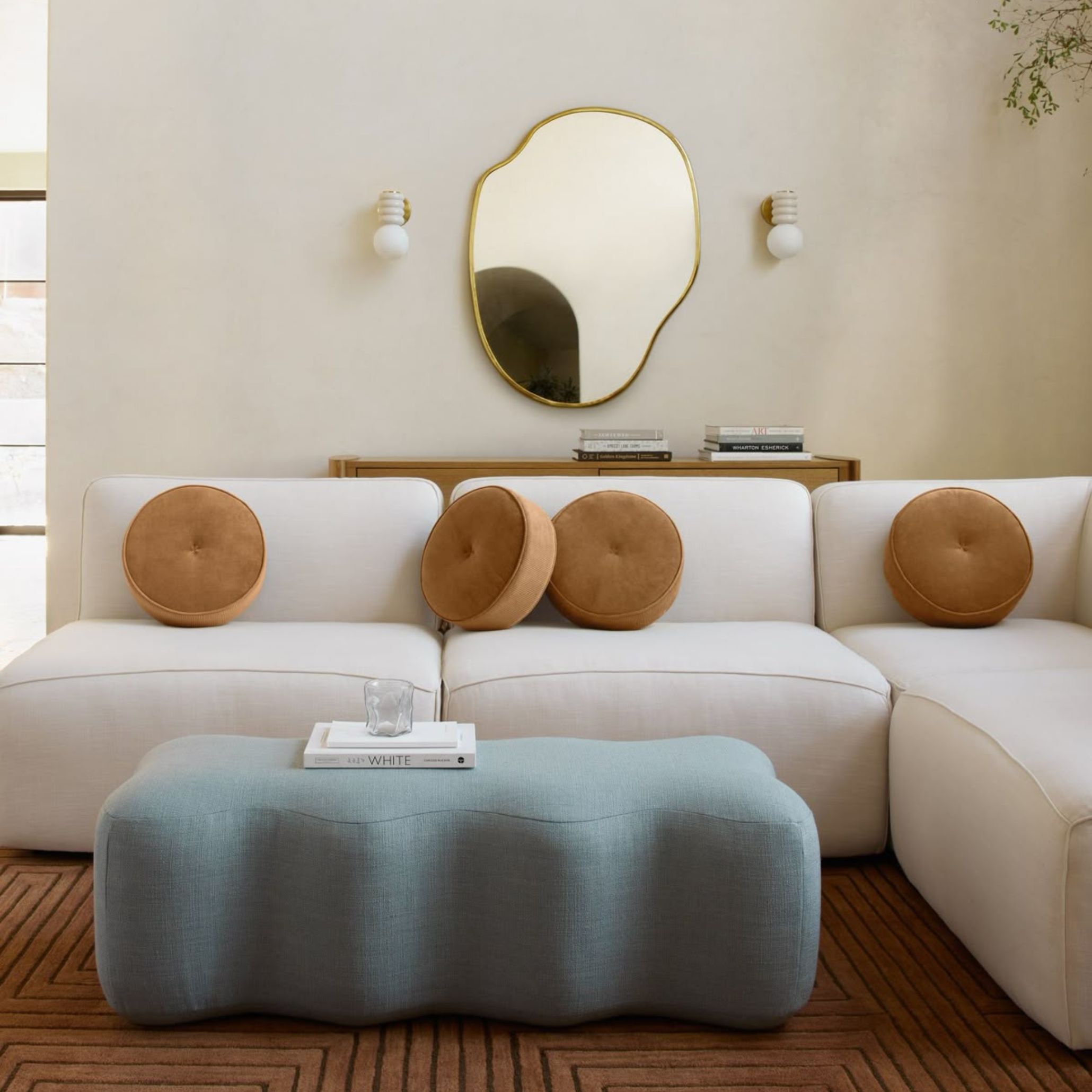 Sala de estar contemporânea com sofá branco, almofadas em cor pastel e detalhes decorativos que seguem uma paleta de cores pastel, criando uma atmosfera luminosa e suave. A composição reflete um design de interiores moderno, onde a cor pastel e a paleta de cores pastel reforçam a harmonia visual e a abordagem refinada do design de interiores.