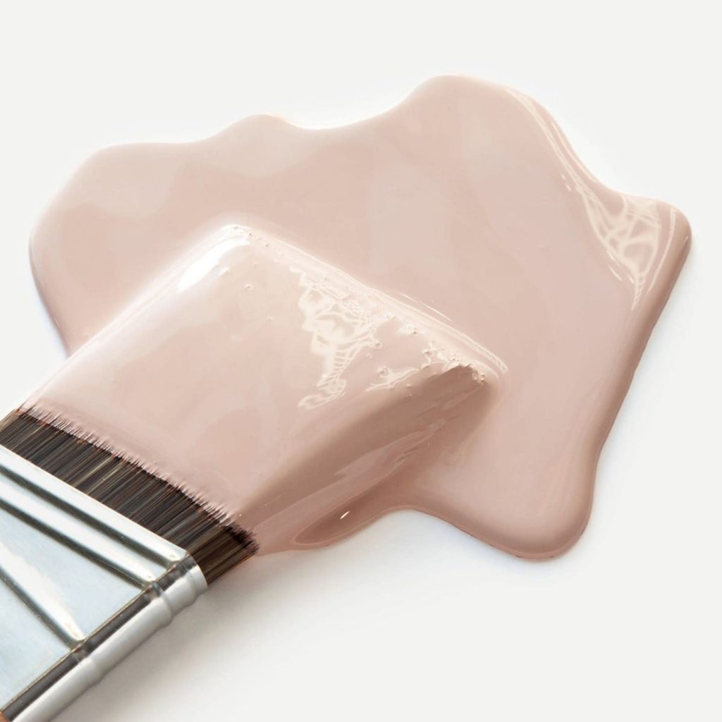 Pincel mergulhado em tinta rosa em cor pastel, destacando a fluidez e suavidade associadas à cor pastel. A imagem evidencia uma paleta de cores pastel que transmite leveza e precisão, frequentemente usada em design de interiores; essa mesma paleta de cores pastel reforça a estética cuidada que caracteriza o design de interiores moderno.