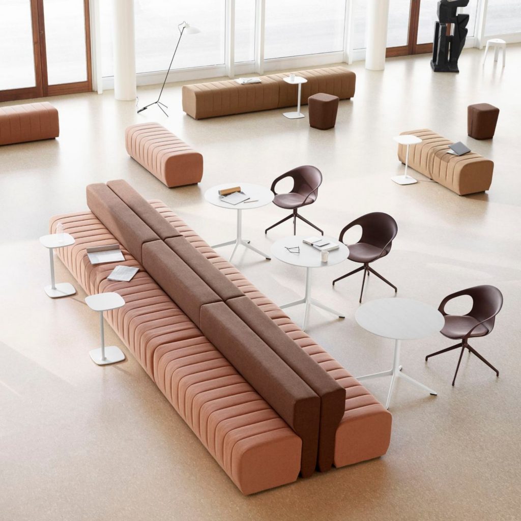 Lounge contemporâneo com bancos modulares em tons terra e mesas redondas brancas, onde apontamentos de cor pastel surgem de forma subtil dentro de um design de interiores funcional. A luz natural e as linhas limpas criam uma paleta de cores pastel discreta, adequada a ambientes públicos. O design de interiores demonstra como a cor pastel pode suavizar espaços amplos, enquanto a paleta de cores pastel acrescenta leveza e coerência visual.