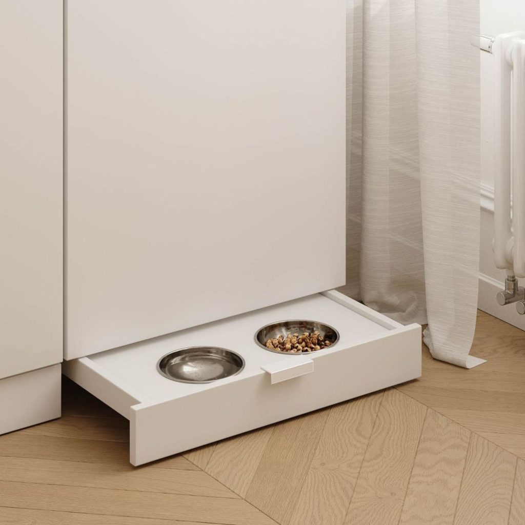 Uma gaveta embutida revela taças de refeição integradas, mostrando como a casa pode acolher animais de estimação através de soluções discretas e elegantes. A estrutura em madeira clara e a decoração minimalista reforçam um design de interiores pensado para manter o espaço organizado, criando um ambiente verdadeiramente pet‑friendly. Aqui, a casa adapta-se às rotinas dos animais de estimação, oferecendo uma zona de refeição prática e higiénica, enquanto o design de interiores e a decoração asseguram coerência visual num espaço totalmente pet‑friendly.