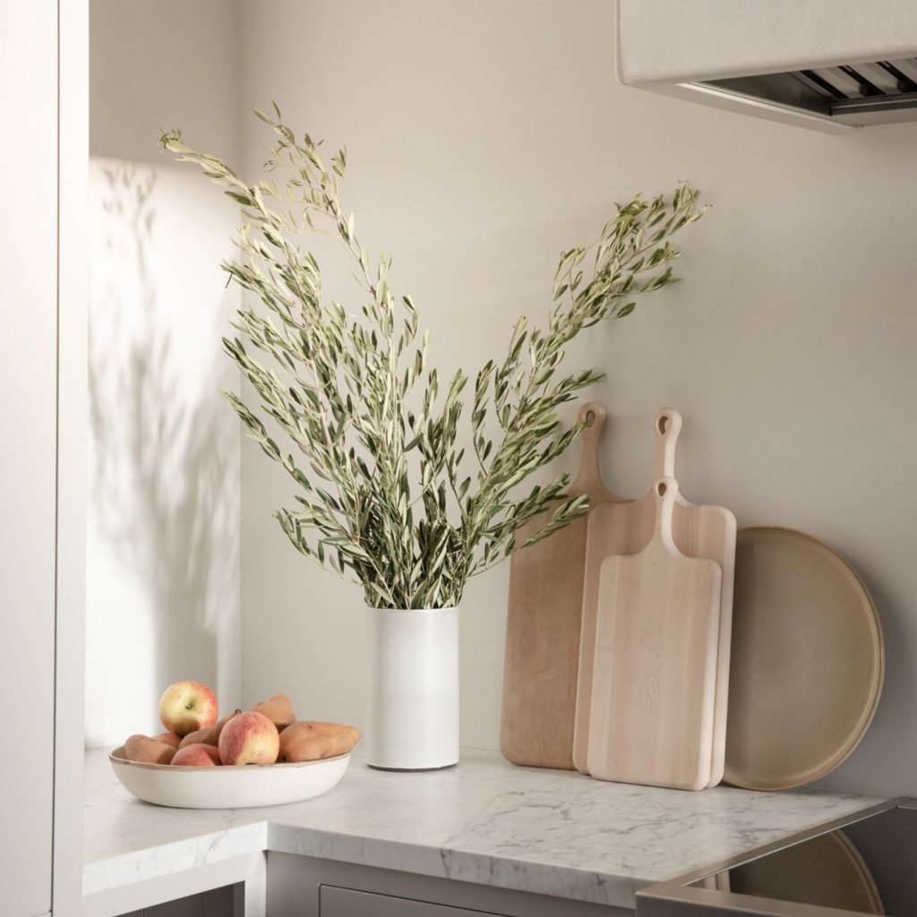 Bancada elegnate com tábuas de madeira, vaso cerâmico e fruteira, mostrando como os utensílios de cozinha podem complementar cozinhas modernas e assumir um papel decorativo; composição equilibrada que une utensílios de cozinha a materiais naturais, refletindo cozinhas modernas orientadas pelo design de interiores e pela integração subtil do design de interiores no ambiente.