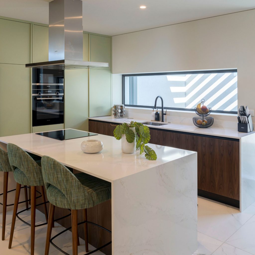 Cozinha luminosa onde os utensílios de cozinha são usados como detalhes decorativos discretos, reforçando a estética organizada típica de cozinhas modernas; a presença equilibrada dos utensílios de cozinha na bancada complementa o ambiente e sublinha a coerência das cozinhas modernas com o design de interiores, integrando o design de interiores de forma harmoniosa.