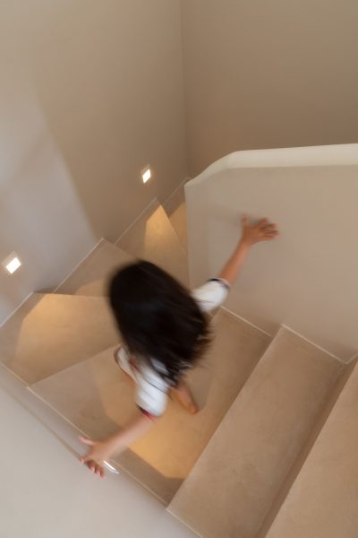 Decoração minimalista que se articula com linhas arquitetónicas suaves dentro de um espaço infantil adjacente. A iluminação embutida reforça a elegância do design de interiores, criando continuidade visual com um projeto de design de interiores de luxo. A composição destaca a serenidade da decoração, acentuando a fluidez do espaço infantil e a sofisticação do design de interiores num projeto de design de interiores de luxo.