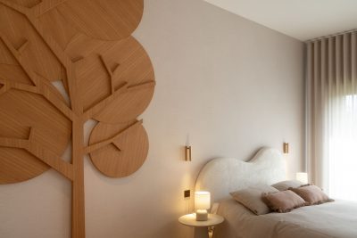 Vista ampla do quarto de criança com painel decorativo em madeira, cama estofada e iluminação suave. A decoração articula elementos lúdicos, a decoração reforça a identidade do ambiente e a decoração cria uma composição equilibrada. O design de interiores integra materiais naturais, o design de interiores privilegia formas orgânicas e o design de interiores promove uma atmosfera acolhedora. Este quarto de criança foi concebido para crescer com os seus utilizadores, fazendo deste quarto de criança um espaço funcional, deste quarto de criança um espaço confortável e deste quarto de criança um espaço elegante.
