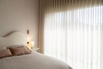 Cama estofada junto a ampla janela com cortinados translúcidos num quarto de criança. A decoração aproveita a luz natural, a decoração cria uma atmosfera leve e a decoração reforça o conforto visual. O design de interiores estabelece uma ligação equilibrada entre materiais e luz, o design de interiores promove serenidade e o design de interiores valoriza a experiência do espaço. Este quarto de criança beneficia de abundante luminosidade, tornando o quarto de criança mais agradável, o quarto de criança mais acolhedor e o quarto de criança mais confortável.