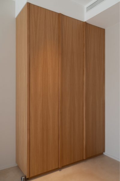 Vista exterior de roupeiro embutido em madeira natural com linhas minimalistas num quarto de criança. A decoração aposta em superfícies depuradas, a decoração privilegia a continuidade visual e a decoração cria uma atmosfera tranquila. O design de interiores integra mobiliário por medida, o design de interiores favorece a funcionalidade e o design de interiores reforça a sensação de amplitude. Este quarto de criança apresenta soluções discretas, permitindo que o quarto de criança permaneça organizado, que o quarto de criança mantenha a sua identidade e que o quarto de criança acompanhe o crescimento da criança.
