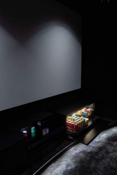 Grande ecrã de projeção acompanhado por móvel técnico com minibar iluminado num sofisticado cinema em casa. O projeto de design de interiores integra soluções de apoio discretas, o projeto de design de interiores organiza os equipamentos de forma funcional e o projeto de design de interiores reforça a experiência de utilização. Este cinema em casa combina tecnologia e conveniência, tornando cada sessão mais confortável dentro deste cinema em casa cuidadosamente planeado.
