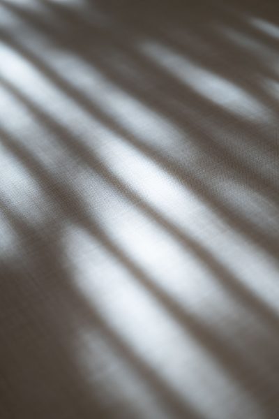 Decoração de quarto sugerida pela luz filtrada que incide sobre a cama de casal, criando um quarto de casal sensorial moldado por um design de interiores subtil. A decoração de quarto ganha profundidade através dos padrões de luz sobre a cama de casal, reforçando a atmosfera calma do quarto de casal concebido com design de interiores cuidado. Esta composição valoriza a decoração de quarto e a presença da cama de casal, consolidando a identidade tranquila do quarto de casal guiado por um design de interiores sereno.
