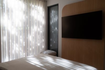 Decoração de quarto marcada pela luz suave que envolve a cama de casal num ambiente sereno, criando um quarto de casal minimalista pensado segundo princípios de design de interiores. A decoração de quarto destaca a presença da cama de casal integrada num quarto de casal onde o design de interiores privilegia linhas limpas e texturas naturais. Cada detalhe reforça uma decoração de quarto equilibrada, com a cama de casal a definir a atmosfera tranquila deste quarto de casal guiado por um design de interiores contemporâneo.