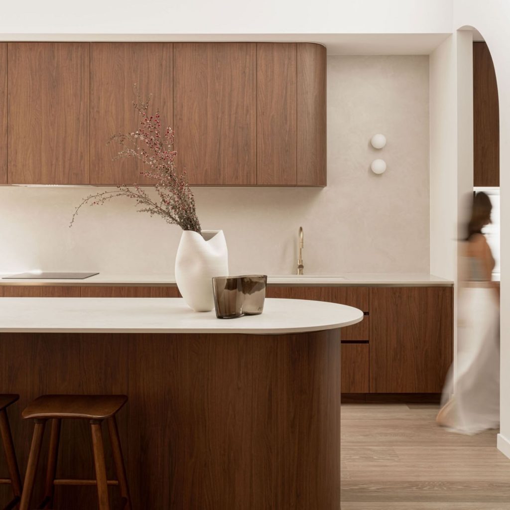 Cozinha contemporânea onde a arquitetura orgânica define a fluidez da casa, articulada com um design biofílico que promove o bem‑estar através de materiais naturais. O design de interiores evidencia a arquitetura orgânica nas formas arredondadas e na luz suave, reforçando o bem‑estar e a ligação emocional à casa através de gestos subtis de design biofílico. A ilha curva e os detalhes esculturais revelam um design de interiores que integra a arquitetura orgânica para criar uma casa orientada para o bem‑estar e para a presença equilibrada do design biofílico.