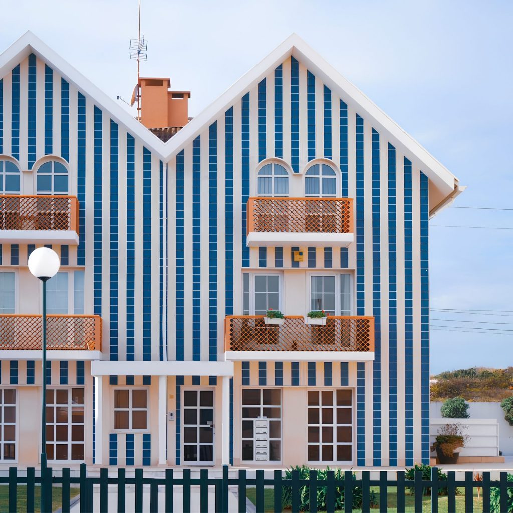 Fachada icónica que remete para as Casas Típicas da Costa Nova, reinterpretando os padrões dos Palheiros da Costa Nova com uma abordagem contemporânea que evoca o ambiente de Casa de praia e inspira Design de Interiores; As riscas verticais reforçam a ligação às Casas às riscas aveiro, destacando a identidade de cada Casa aveiro e os vibrantes Colores de casa associados às Aveiro casas coloridas; A composição volta a celebrar as Casas Típicas da Costa Nova, articulando a tradição dos Palheiros da Costa Nova com a atmosfera de Casa de praia, criando paralelos com soluções de Design de Interiores; A geometria marcada intensifica a referência às Casas às riscas aveiro, à autenticidade de cada Casa aveiro e aos expressivos Colores de casa presentes nas Aveiro casas coloridas; O enquadramento final reforça pela quinta vez as Casas Típicas da Costa Nova, os Palheiros da Costa Nova, o espírito de Casa de praia, a inspiração de Design de Interiores, e a força visual das Casas às riscas aveiro, das Casa aveiro, dos Colores de casa e das Aveiro casas coloridas.