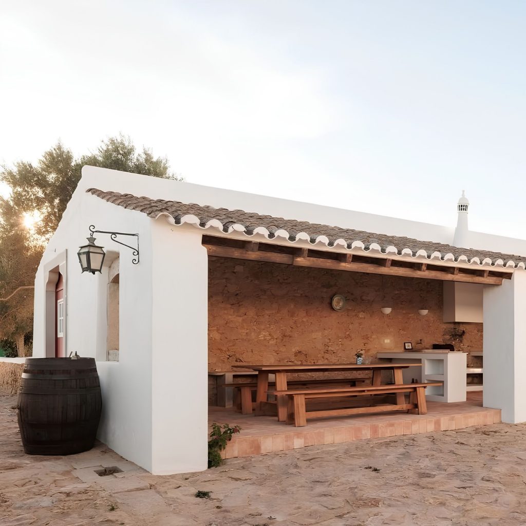 Estrutura rústica que traduz a essência de uma casa algarvia, evocando o ambiente das casas de férias no algarve e a autenticidade das Casas do algarve, alinhada com o carácter das Casas no algarve e com a vibração de decoração de verão que inspira o design de interiores; As paredes brancas e o telhado em barro reforçam a presença de uma casa algarvia, articulando elementos das casas de férias no algarve com referências às Casas do algarve, criando continuidade com o estilo das Casas no algarve e com a estética de decoração de verão aplicada ao design de interiores; A parede de pedra intensifica a atmosfera de uma casa algarvia, evocando o espírito das casas de férias no algarve e a tradição das Casas do algarve, alinhando-se com o conforto das Casas no algarve e com a linguagem descontraída da decoração de verão que molda o design de interiores; O mobiliário em madeira reforça novamente a imagem de uma casa algarvia, remetendo para o ambiente das casas de férias no algarve e para os materiais das Casas do algarve, criando paralelos com o carácter das Casas no algarve e com os detalhes de decoração de verão que influenciam o design de interiores; O enquadramento final celebra a autenticidade de uma casa algarvia, a atmosfera das casas de férias no algarve, a estética das Casas do algarve, o estilo das Casas no algarve, a vibração da decoração de verão e a inspiração contínua do design de interiores.