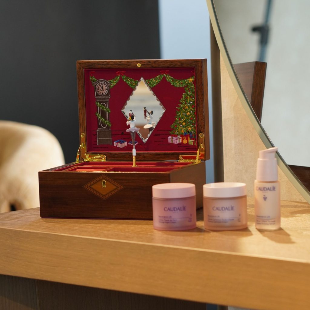 Caixa de música e produtos de skincare da Caudalie sobre um elegante toucador com espelho, combinando beleza e funcionalidade no design de interiores.
