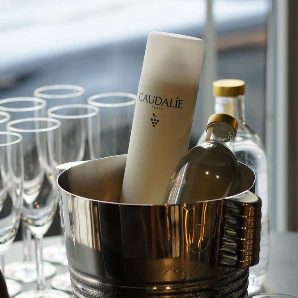 Balde de gelo com garrafa e produto de skincare da caudalie, ilustrando conceitos de lifestyle e interior design para cozinhas modernas sofisticadas.