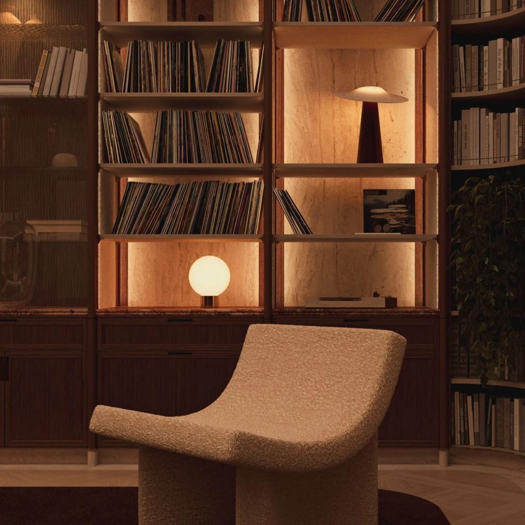 Espaço acolhedor de biblioteca em casa com iluminação embutida na estante em madeira, dispondo de elegantes estantes para livros, um cadeirão moderno em primeiro plano e peças de decoração num conceito sofisticado de design de interiores.